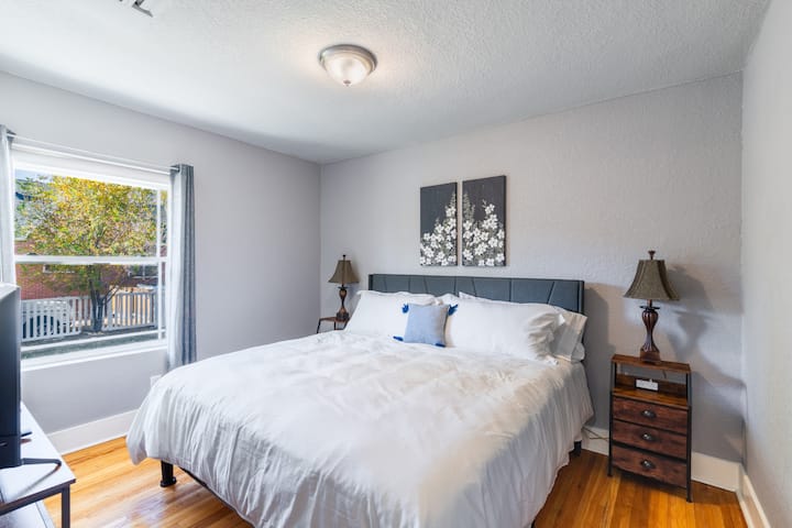 Mapumziko ya kustarehesha na kitanda cha mfalme na vivuli vya kufanya chumba kuwa giza.