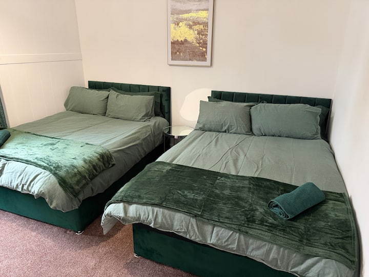 卧室配有两张双人床、干净的床上用品和床头灯，适合共享住宿或团体住宿。