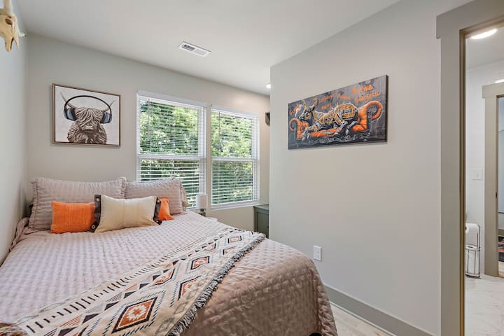 Relájate en un dormitorio de temática country con una acogedora cama tamaño queen vestida con sábanas suaves, cálidos detalles de madera rústica y una decoración de inspiración vintage. Un televisor inteligente ofrece una transmisión sencilla, creando un refugio encantador y relajante después de un día de aventura.