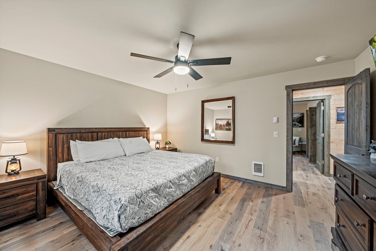 Pokojná spálňa s manželskou posteľou, rustikálnym nábytkom, stropným ventilátorom a množstvom priestoru na odpočinok.