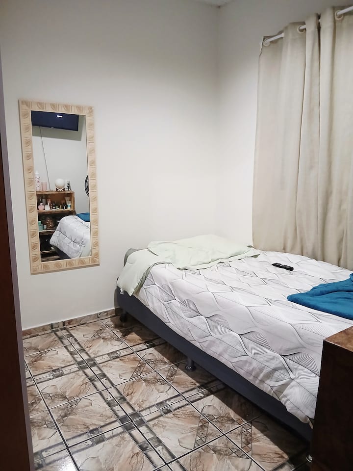 Dhomë teke në katin përdhes me televizor inteligjent, gardërobë, ventilator kolone Britânia BVT450 Maxx Force dhe një dyshek tjetër në dispozicion 