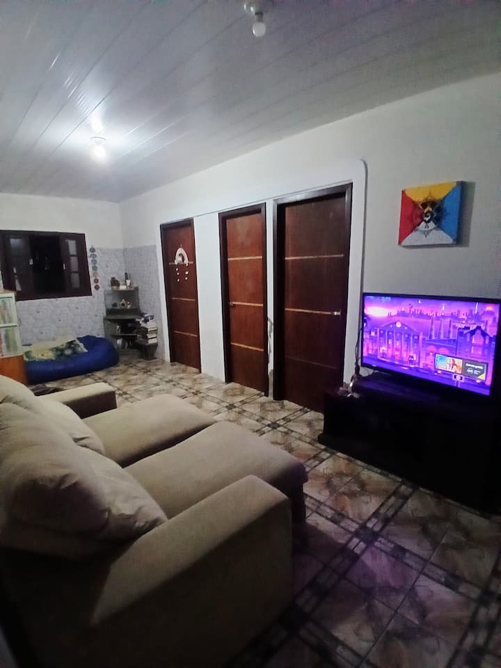 dhomë në katin përdhes me një divan që paloset, dy pufë, televizor me Roku TV, altoparlant Bluetooth 