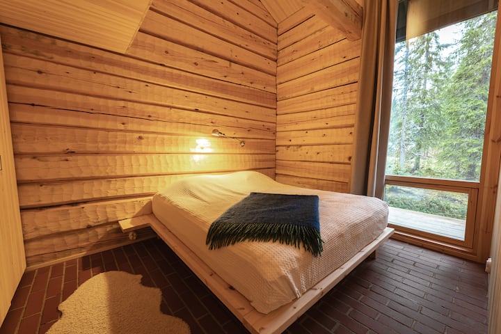 Valoisa päämakuuhuone, jossa on suuri ikkuna lumiseen metsään.