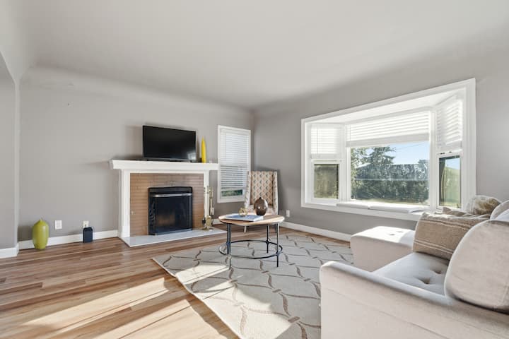 ห้องนั่งเล่นที่มีแสงแดดดีพร้อมวิวหน้าต่างเบย์ ที่นั่งสบาย ๆ เตาผิง และสมาร์ททีวี เป็นที่พักผ่อนที่อบอุ่นระหว่างการผจญภัย 