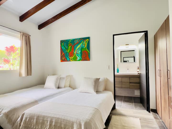 Habitación de 12 metros cuadrados con armario, televisor inteligente y dos camas individuales, cada una de 1 m x 1,90 m