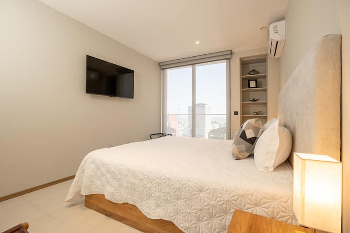 Amplia habitación principal con cama king size, aire acondicionado, TV, baño privado y balcón con vista a la ciudad. Perfecta para descansar y disfrutar de privacidad con todo el confort.