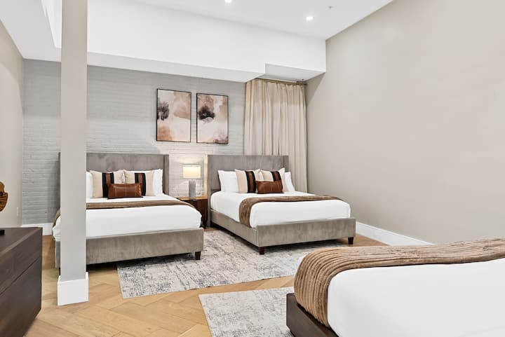 ห้องนอนกว้างขวางพร้อมเตียงควีนไซส์ 2 เตียงโทนสีอ่อนและงานศิลปะที่หรูหราเหมาะสำหรับกลุ่มหรือครอบครัว