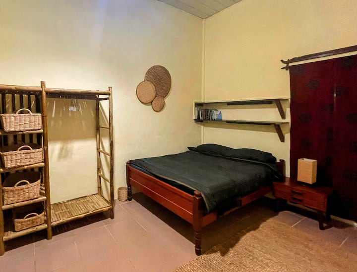 Second bedroom (downstairs) – double bed with good mattress, tribal sarong linens, traditional Khmer wooden headboard, and a little shelf of books for late-night reading. Cool tiled floor, quiet corner of the house, and perfect for deep sleep. ️