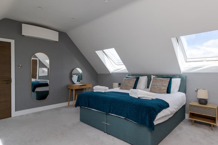 Bright and stylish bedroom with vaulted ceilings, skylights, and modern décor. A calm and comfortable space, perfect for relaxing and enjoying a peaceful night’s sleep