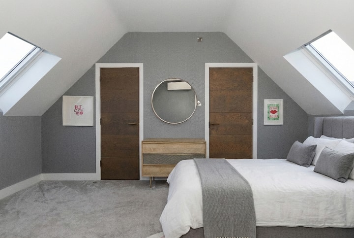 Bright and stylish bedroom with vaulted ceilings, skylights, and modern décor. A calm and comfortable space, perfect for relaxing and enjoying a peaceful night’s sleep