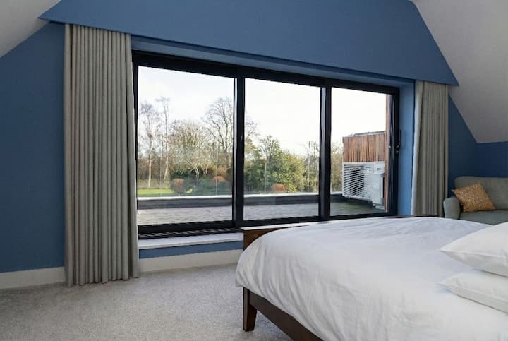 Bright and comfortable bedroom featuring large windows with peaceful outdoor views, creating a calm and relaxing space to unwind.