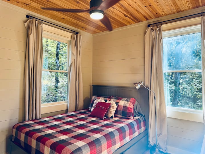 Cómodo dormitorio con cama tamaño queen y ventanas con vistas relajantes.