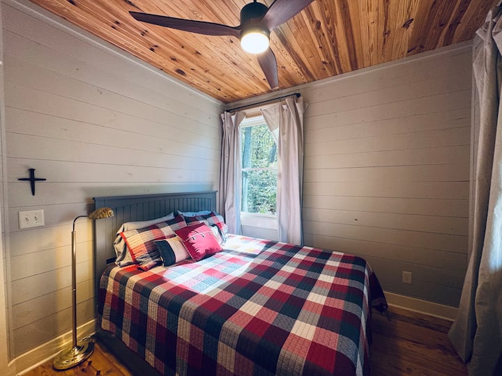 Acogedora habitación con una cama tamaño queen y una ventana que llena el espacio con luz natural, creando un refugio tranquilo para descansar y relajarse.