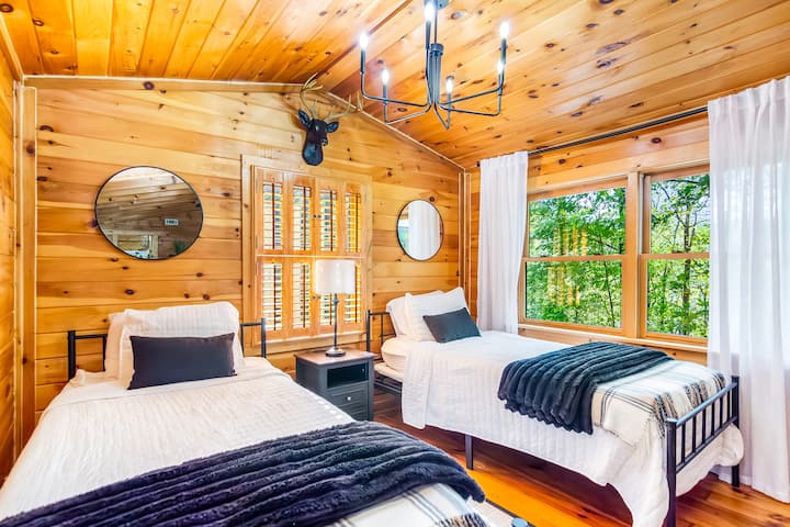 Habitación doble con decoración clásica de cabaña, grandes ventanales y vistas al bosque.