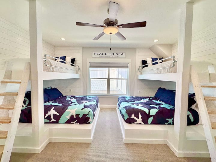 Aviation-themed bunk room with bold blue bedding and natural light