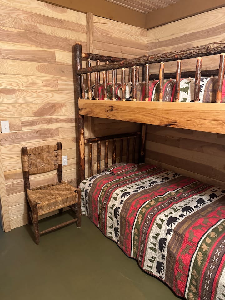 Inviting second bedroom with a comfortable bunk bed, warm wood textures, and simple, clean décor. Ideal for families or friends looking to enjoy a quiet getaway on a spacious 30-acre property with its own waterfall.