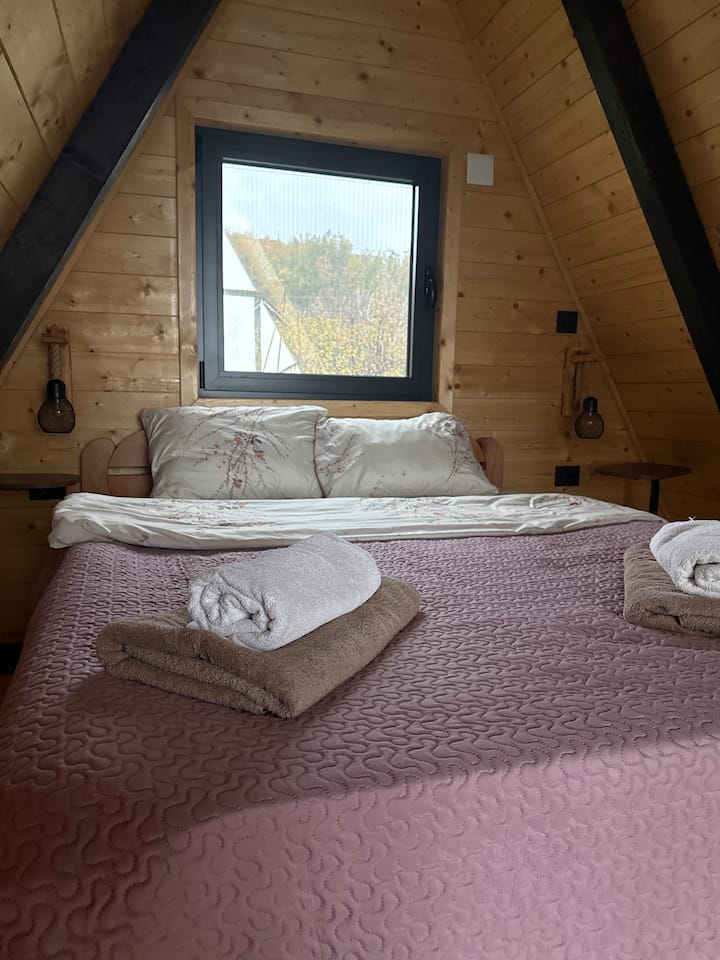 Acogedor dormitorio en forma de A que ofrece serenidad de madera y vistas tranquilas, perfecto para un retiro en pareja después de disfrutar de la sauna, el jacuzzi y la piscina climatizada.