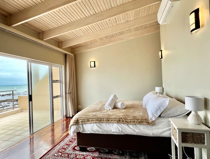 Amplio dormitorio principal con acceso directo al patio, vistas ininterrumpidas al mar y un espacio de trabajo dedicado, perfecto para una estancia relajante frente a la playa en Swakopmund.