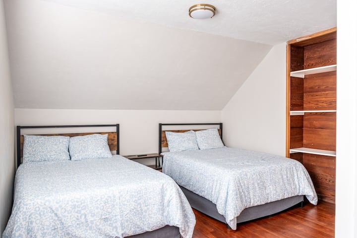 Dhomë e gjerë në katin e sipërm me dy krevate dopio dhe televizor.