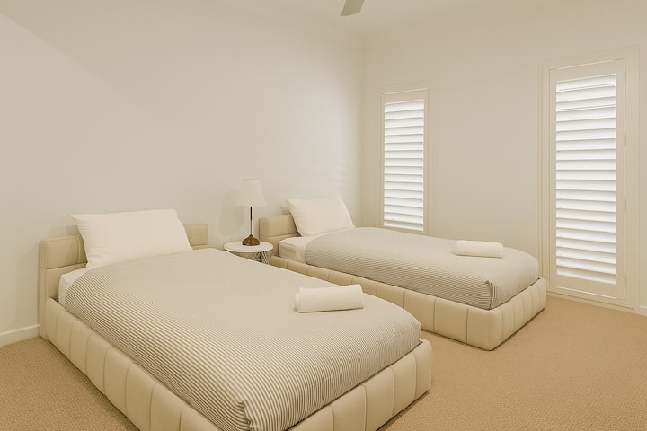 Cuarto dormitorio elegante con dos camas individuales y una decoración serena, diseñado para la comodidad, el espacio y un toque de lujo discreto.