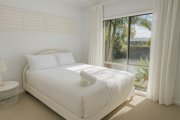 Elegante segundo dormitorio con cama tamaño queen, que combina comodidad y simplicidad, completo con ropa de cama de calidad y tonos neutros relajantes.