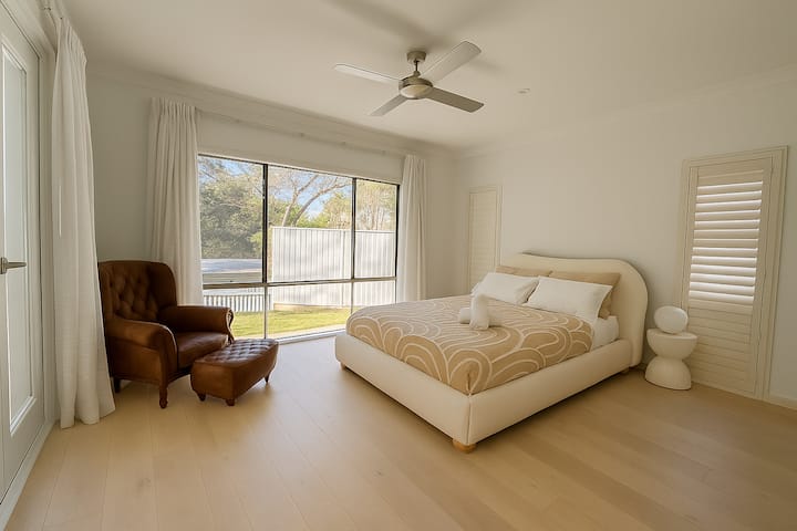 Amplio dormitorio principal con una cama lujosa, iluminación suave y decoración relajante: el refugio perfecto después de un día junto al arroyo. Este dormitorio tiene su propia ducha y baño privado.