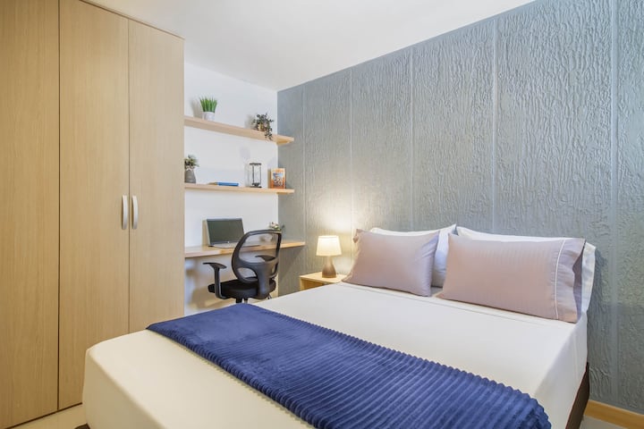 Habita el confort: cama doble impecable, ventilador móvil,  iluminación cálida, escritorio para teletrabajo y diseño moderno que inspira bienestar y productividad.