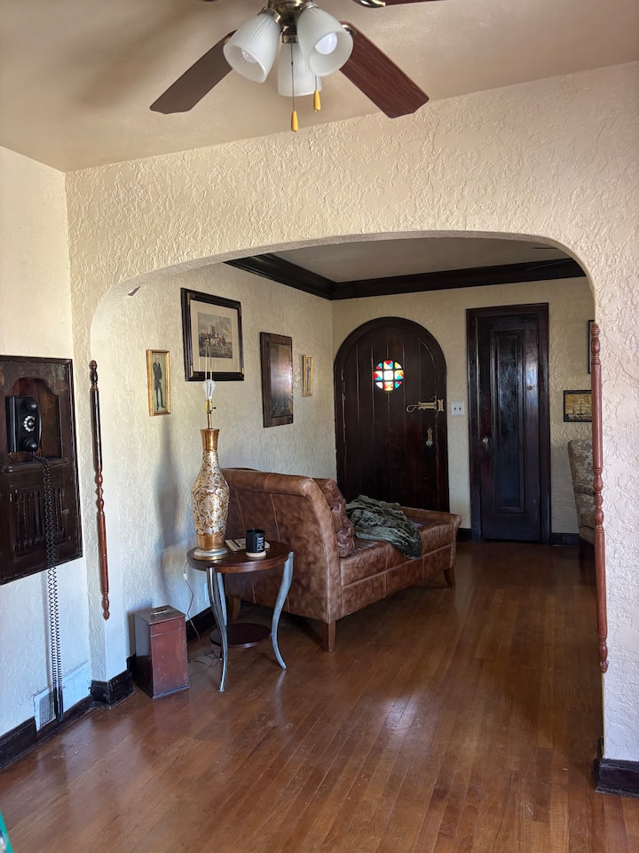 Tudor living room with oak trim, vintage artwork, and an arched doorway