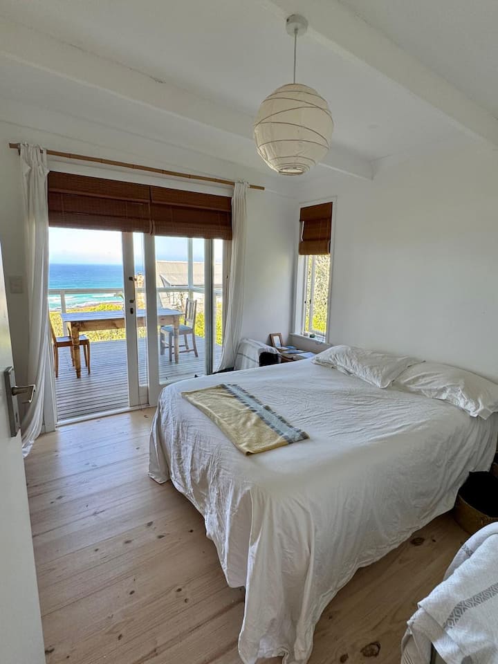 Un pequeño dormitorio con una cama doble y baño en suite y con puertas correderas en la terraza delantera.