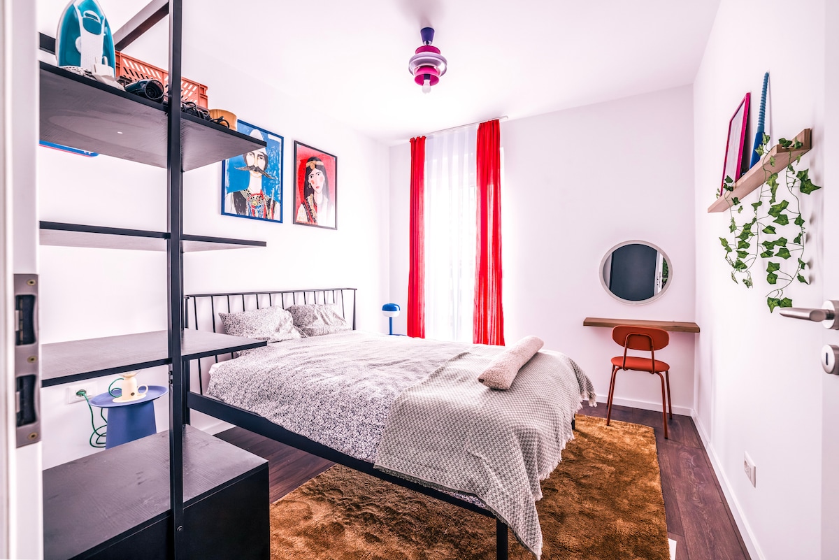 غرفة نوم كبيرة ومريحة بسرير مزدوج بحجم كوين وطاولة عمل ورف مفتوح. 