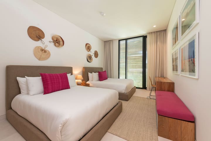 Dormitorio con 2 camas tamaño queen y baño privado adjunto.