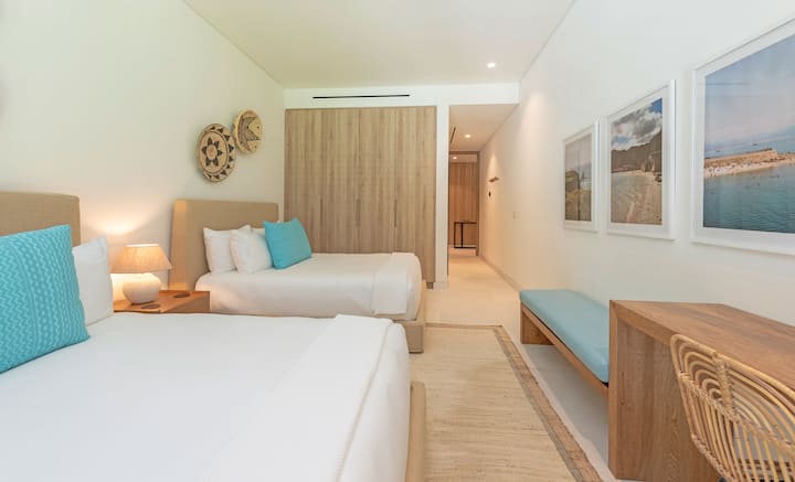 Dormitorio con 2 camas tamaño queen y baño privado adjunto.