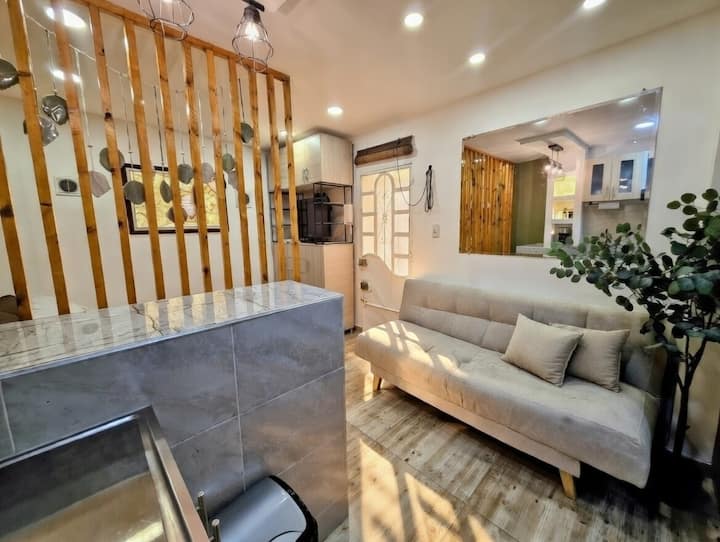 Dhomë e ndriçuar dhe elegante në Casa Hotel Victoria Bogotá. Divan i butë (krevat shtesë), drita të ngrohta LED, ndarës dhome prej druri i punuar me dorë me varëse, bar dhe pak gjelbërim. Çlodhu me stil pranë Teusaquillo, Chapinero dhe Zona T! Banesa jote e përkryer në qytet.