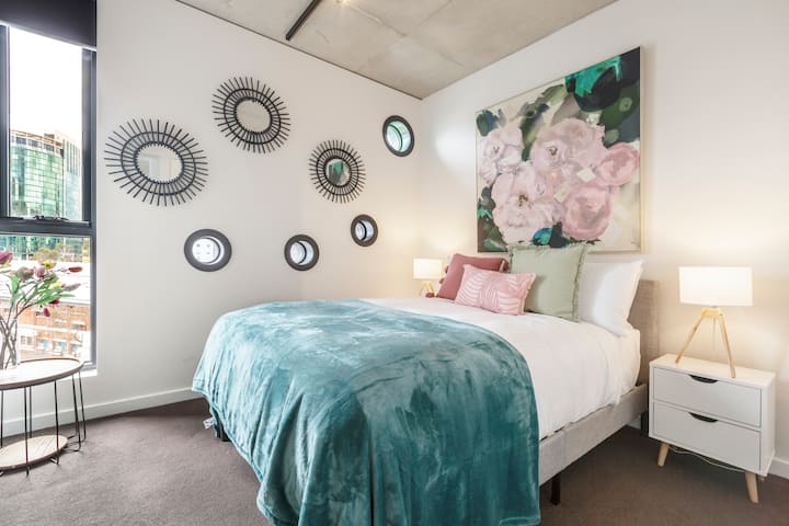 Druhá spálňa má manželskú posteľ s kvalitnou posteľnou bielizňou, umeleckým dekorom a mäkkými farebnými tónmi, ktoré vytvárajú príjemnú atmosféru.