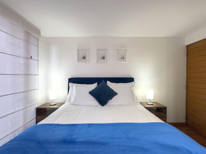 Habitación principal con cama queen, ropa de cama confortable y TV.