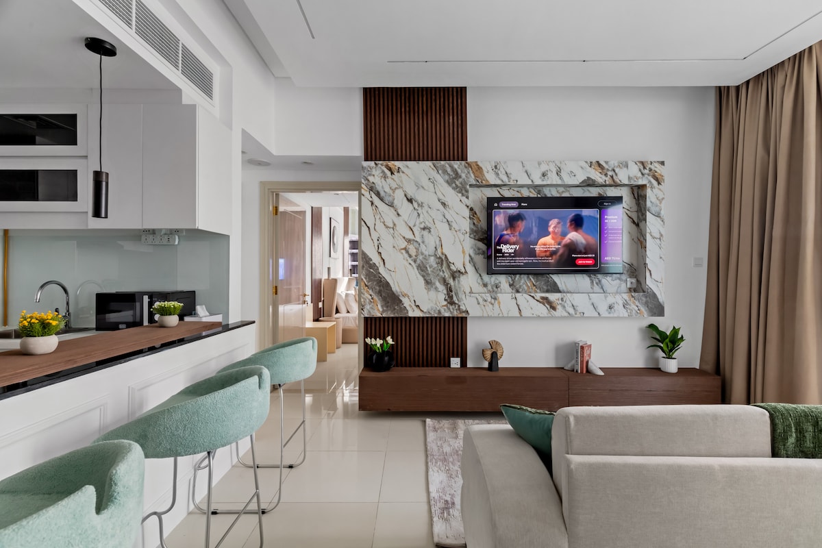 Štýlový otvorený obývací priestor s vlastnou mramorovou stenou a raňajkovým barom s vysokým sedením.