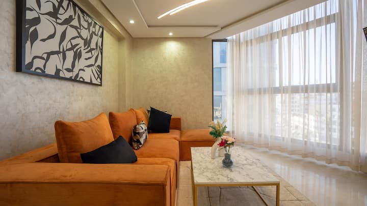 Acogedora y luminosa sala de estar con sofá 
cómodo y con elegantes toques decorativos. Gran ventana con vistas panorámicas de la ciudad. La iluminación ambiental y el mobiliario de diseño crean un ambiente cálido y acogedor.