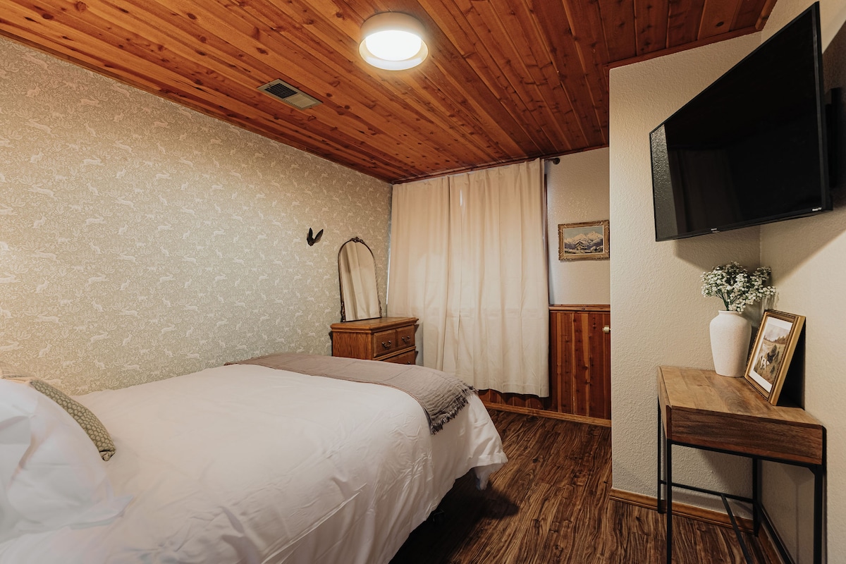 Een warme slaapkamer met houten plafonds en zacht beddengoed.