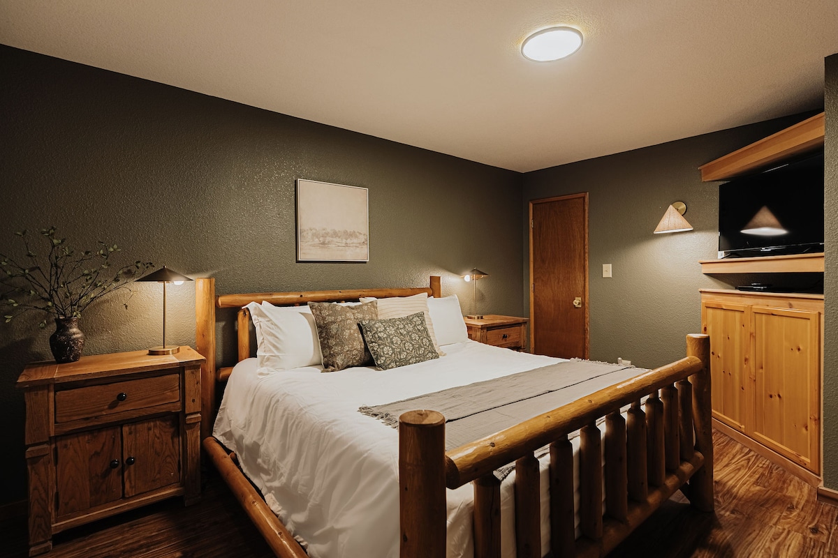 Een warme slaapkamer met een houten bedframe en zacht gelaagd beddengoed.