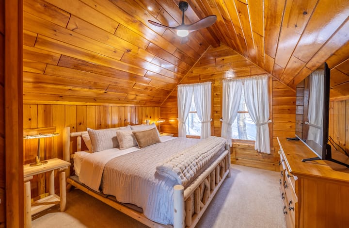 Upstairs master bedroom, with comfy king bed, night stands, tv, dresser, closet with hangers, and bench