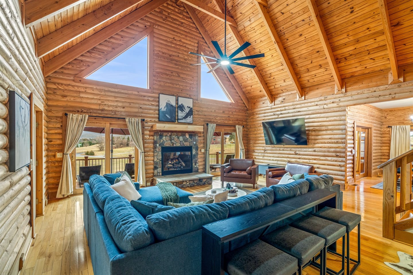 Spacious living area with a stone fireplace and large windows framing scenic mountain views all day long.