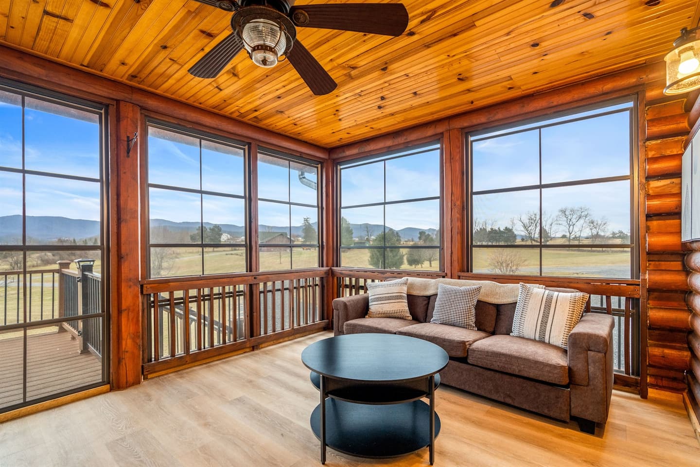Bright sunroom with wraparound windows, cozy seating, and stunning mountain views.