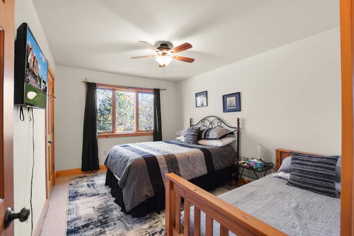 Bedroom 2 sits on the main floor and offers both a queen and twin bed—perfect for families or friends. A ceiling fan and TV make it an extra cozy spot to unwind.