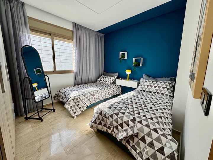 Chambre double lumineuse : deux lits simples confortables, des draps doux et un mur bleu vif. Parfaite pour les amis, les enfants ou les collègues en visite à Rabat, cette chambre paisible allie confort, style et lumière naturelle.