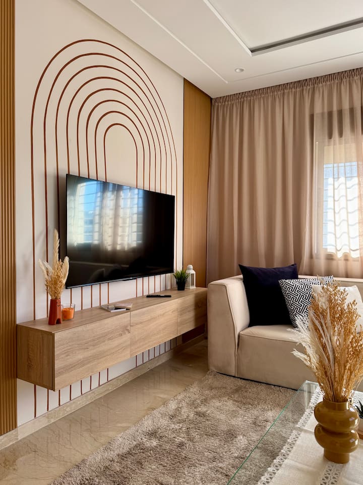 Coin de divertissement confortable : détendez-vous dans cet espace élégant avec une télévision murale, des tons chauds et un design moderne. Parfait pour les soirées cinéma ou pour se détendre après avoir exploré le centre animé de Rabat.