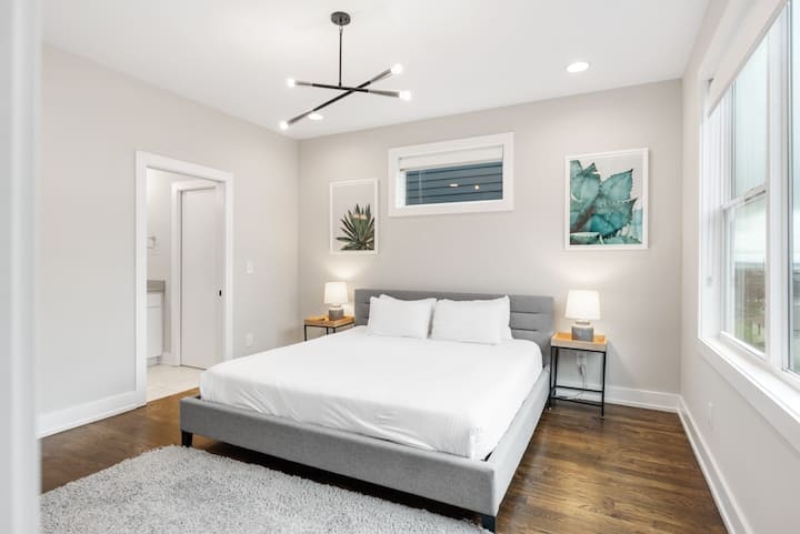 Serene king bedroom with modern design, plush bedding, bedside lighting, and natural light—clean, quiet, and perfect for a restful night’s sleep.