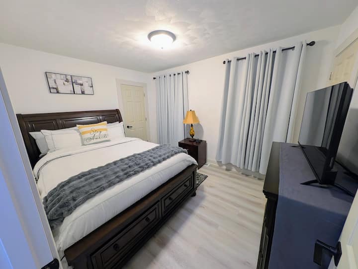 Amplio dormitorio con cama tamaño queen, televisor y dos vestidores.  