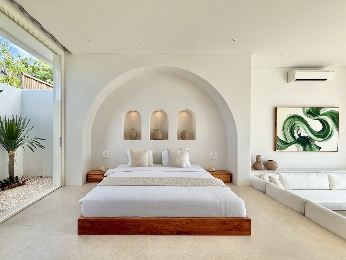 A refined bedroom featuring a plush king-size bed, a large built-in closet, and a private ensuite bathroom, enhanced by warm wooden details and natural light.