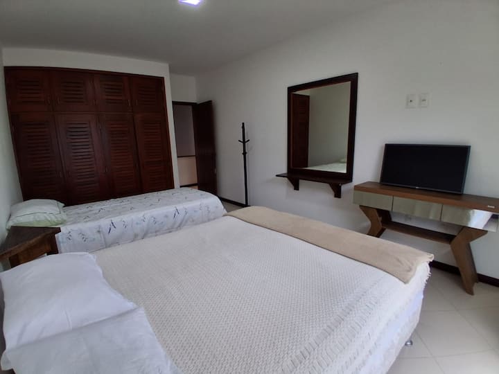 宽敞的卧室，阳台可俯瞰海滩，配有双人床和带额外床垫的双层床。