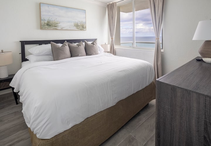 Pumzika katika chumba cha kulala cha kifalme chenye utulivu kilicho na mashuka meupe, mito ya kitani na mapambo ya ufukweni yenye utulivu. Madirisha makubwa yana mandhari maridadi ya bahari, yakijaza chumba kwa mwanga wa asili na kuunda mapumziko ya amani kwa usiku wa kupumzika.